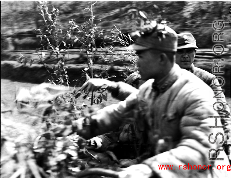 Chinese soldiers riding a motorized vehicle during exercises in southern China, probably Yunnan province, or possibly in Burma, riding a motorcycle.