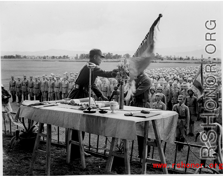 Chinese soldiers in ranks observe ceremonial hand off of banner or flag.