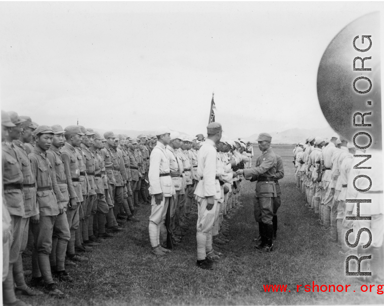 Chinese soldiers stand in ranks during exercises, being inspected by officers.