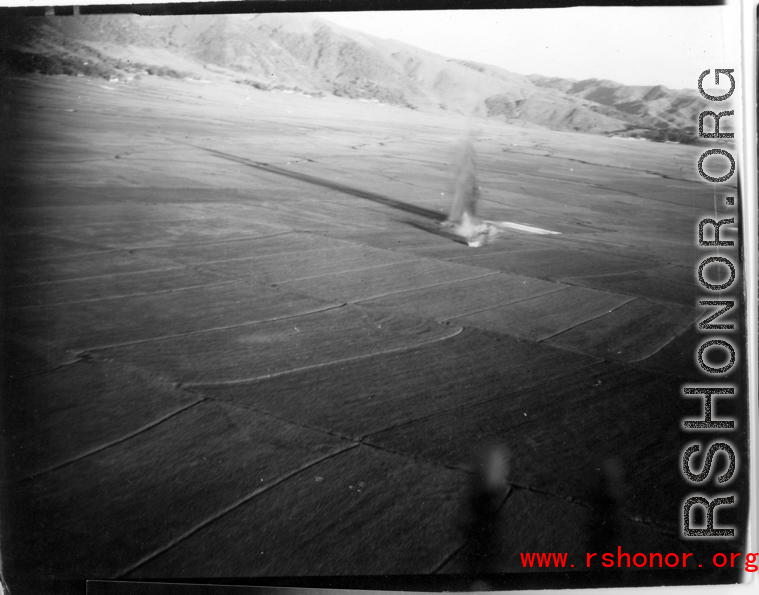 Image of a very odd explosion near Tengch0ng--out in the  middle of a rice paddy. What this a bomb blast or an aircraft crash? Image taken from B-25 Mitchell bombers during battle with Japanese ground forces, flying near Tengchung (Tengchong), near the China-Burma border in far SW China.