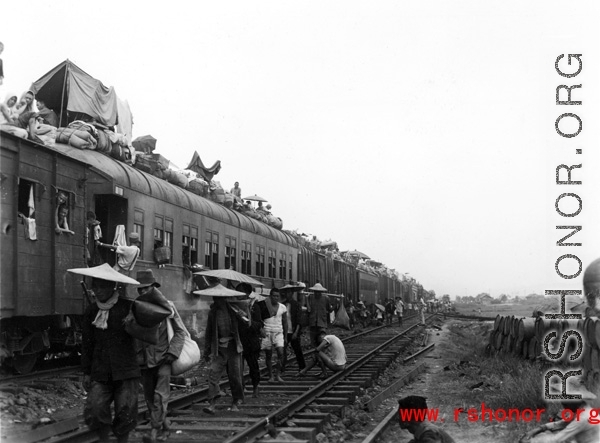 Fleeing people on (and on-top) of train during Chinese civilian evacuation in Guangxi province, China, during WWII, during the summer or fall of 1944 as the Japanese swept through as part of the large Ichigo push. During WWII.