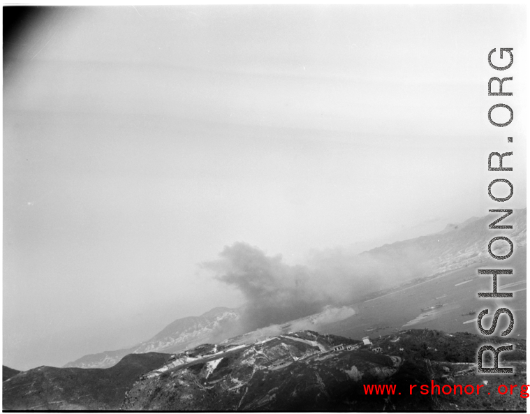 Smoke arises in the distance after an American attack on Hong Kong harbor during WWII.