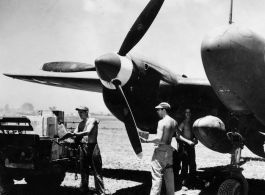 GIs move supplies between a truck and a F-5 (P-38)--not usually considered a cargo carrier--including a box labeled "Curtiss Candy Co." along with cartons of "plum base." In the CBI during WWII.   Photo from W. T. Basore.