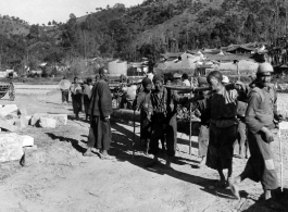 Laborers in a rural location in SW China carry larges timbers. During WWII.