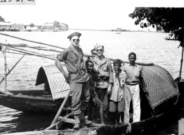 Two GIs on a boat with a family in India or Burma. During WWII.