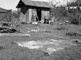 Local people in China: Men prepare to cook rice in a small shack next to American GI tents.  From the collection of Eugene T. Wozniak.