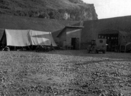 "The Latest In Shops And Equipment--This a picture looking into a revetment that served as our work area and engineering area at Luichow [Liuzhou], China. Lt. Sohl's office was in the little shack at the right and all our tools and equipment was in the tent. We changed a lot of B-24 engines in this revetment along with replacing blown out tires and doing sheet metal repair work. We worked here until the Japanese forced us to evacuate the base and return to Luliang."