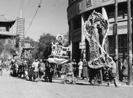 A colorful parade--with floats, marchers, and music--for a local festival in Kunming, China, during WWII.