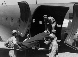 A GI is lifted on a stretcher into a C-47 for transport for medical care in the CBI during WWII.