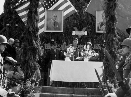 Burma Road dedication ceremony in Kunming, China, on February 4, 1945, during WWII. Review of first convoy (or one of the first convoys) to reach China. General view of the stage and reviewing party, with American and Chinese dignitaries, soldiers, and civilian VIPs. An American band plays, and an honor lines on both sides of the center carpet stand in formation.  Official dignitaries at the ceremony included, on the Chinese side, such figures as General Lung Yun, Governor of Yunnan Province,  Gen. Wang Yu-