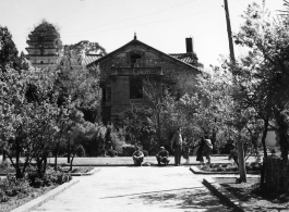 Americans and Chinese on an administrative (ie, university or similar) or a housing compound, with a Buddhist pagoda in the background--indication that the grounds were once a Buddhist temple, later appropriated and converted during Nationalist social movements.