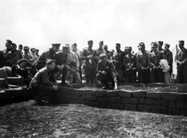 American and Chinese military leaders meet to discuss battle in the CBI using a topographical model made of adobe bricks and dirt. During WWII. Notice what appears to be a woman in civilian clothing sitting on a sedan chair on the left.  (Images provided via Tony Strotman)