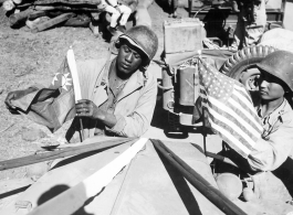 "A U.S. Army soldier and a Chinese soldier place the flag of their ally on the front of their jeep just before the first truck convoy in almost three years crossed the China border en route from Ledo, India, to Kunming, China, over the Stilwell road."