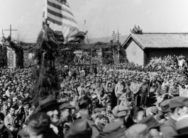 Burma Road dedication parade and ceremony in Kunming, China, on or around February 4, 1945, during WWII. Review of first convoy (or one of the first convoys) to reach China. Ranks of soldiers and civilians. Note movie camera filming on far right, and just below that, a couple of African-American officers.