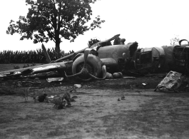 Wrecked B-25 Mitchell bomber on the ground in the CBI. The wreck was apparently at an air base, and probably on take-off, as the craft is sprayed with fire-retardant foam, and bombs are scattered about the wreck site. During WWII.