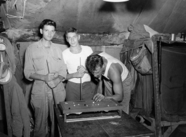 Engineers of the 797th Engineer Forestry Company pose while playing at a tiny pool table in their tent in Burma.  During WWII.