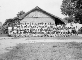 Local people in Burma near the 797th Engineer Forestry Company--A large group of children pose before a village school (most likely a missionary school) in Burma.  During WWII.