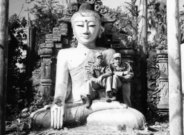 GIs sit on Buddha statue in remains of Buddhist temple in Burma.  During WWII.