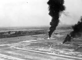 Japanese planes burning in revetments at Chiang Mai air base, Thailand. Note scattered puffs of dust on ground from machine gun or cannon fire.  22nd Bombardment Squadron.