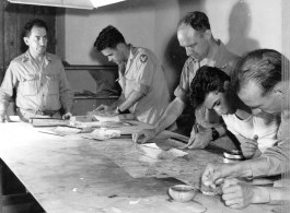 "Mosaic laying" at photo lab of the 24th Mapping Squadron--cutting and pasting numerous high-resolution aerial images together onto a board to create a wide view. June 10, 1944.