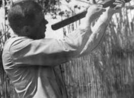 Phil Eppley shooting native crossbow in 1944, in Szemao or Mengsa, during WWII. Note native stockade of bamboo in the background. 