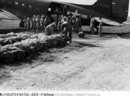 Bundles of food and ammunition being loaded aboard a C-47 of the 14th Air Force Transport Unit. They will be kicked out to Chinese troops cut off from ground supply in eastern China.