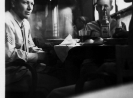 Everett Lull, Paul Hunt, and James Vaughn relaxing over a few drinks and food in the CBI, most likely on or near an American air base in China, during WWII.