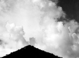 A village near Yangkai, Yunnan province, China: Bright clouds high in the sky. During WWII.