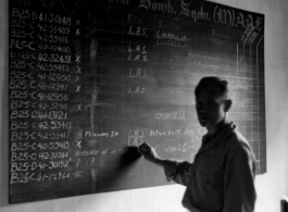 An unidentified individual at the aircraft status board for the 22nd Bombardment Squadron, at Chakulia Air Base, India.The photo was taken after August 3 and September 10, 1943.