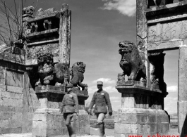 Two Chinese soldiers walk through a ceremonial gate in Yunnan province during WWII.