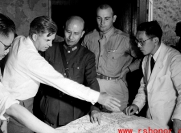 VIPs from both the US and China talk things over during WWII at a base somewhere in China.  Senator Henry Wallace gestures over the map, next to Chiang Kai-shek.