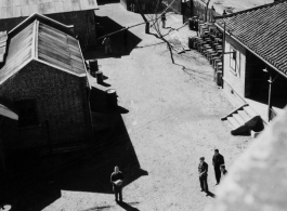 Kunming Hostel: "Hostel #3 from roof of HQ, 44 Gal. gas drums nearby"  Note man holding basketball in foreground.