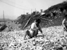 A worker crushing rock by hand at a base in southwest China, during WWII.