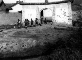 A village gate in a style once typical of Yunnan and Guizhou province, with a saying "Mountains Lofty and Clouds Deep" (“岭峻云深”) written above the gate. During WWII.  Photo from George Pollock.