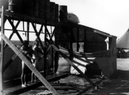 GIs shower outside under barrels, in the CBI during WWII.