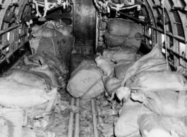 Bags are piled in cargo plane ready for aerial drop to Allied troops. Some will be dropped with parachutes to slow the drop (those in the distance in the image), and some will be dropped directly. In the CBI.