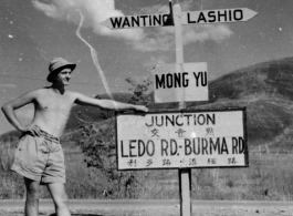 GI leans against sign at junction of Ledo Road and the Burma Road, during WWII.