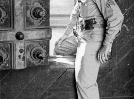 Frank Bond of the 40th Photographic Reconnaissance Squadron squeezes through a small door in a massive gate of a Hindu temple in Madras, India, during WWII.  Photo from Glenn S. Hensley.