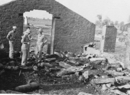 GIs look over destroyed bomb stores in destroyed store building. During WWII.  Photo from J. E. Thorton.