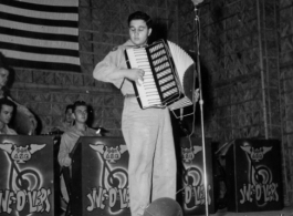 A GI plays accordian, while the "Jive-o-Lieps" of the 54th Air Service Group wait their turn In the CBI during WWII.