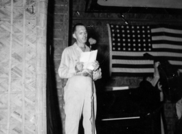 A GI reads from a script during a variety show, while the band Jive-o-Lieps prepares to play music in the CBI during WWII. 54th Air Service Group.