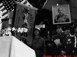 Burma Road dedication ceremony in Kunming, China, on February 4, 1945, during WWII. Review of first convoy (or one of the first convoys) to reach China. General view of the stage and reviewing party, with American and Chinese dignitaries, soldiers, and civilian VIPs. An American band plays, and an honor lines on both sides of the center carpet stand in formation.  Official dignitaries at the ceremony included, on the Chinese side, such figures as General Lung Yun, Governor of Yunnan Province,  Gen. Wang Yu-