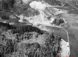 A fortified karst rock outcrop, certainly with a Japanese troops dug in or nearby, is bombed in southern China or Indochina during WWII. Notice the bomb crater to the left--the site has been bombed before.