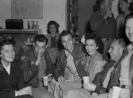 Celebrities visit and perform at Yangkai, Yunnan province, during WWII: GIs and medical staff share a meal with celebrities, including Betty Yeaton seated, Jinx Falkenburg standing in right background, and a Hollywood movie star on far left, and Mary Landa seated against back wall.