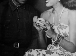 Celebrities visit and perform at Yangkai, Yunnan province, during WWII: Jinx Falkenburg poses with a Chinese soldier while she autographs a tennis ball.