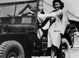 Paulette Goddard hanging onto a Y-force jeep, during WWII.