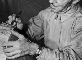 A VIP visitor signs a short-snorter on the back of an American GI, during WWII.  An American in the CBI.