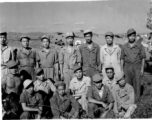 Chinese aircraft mechanics and engineers pose at an air base in China during WWII. Behind them are damaged airplanes used for parts.