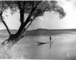 Chinese man standing on a boat in a lake in China during WWII.