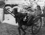 Wealthy woman rides rickshaw in China during WWII.